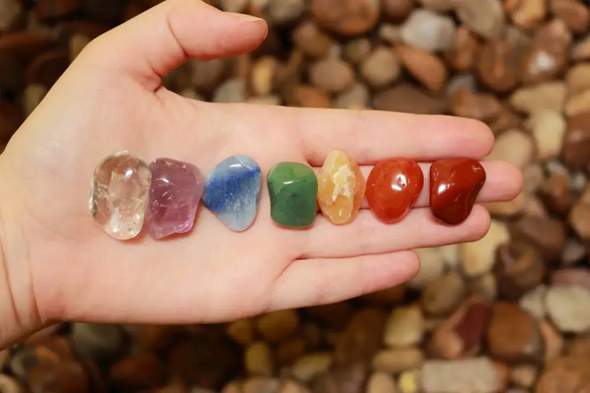 Siete piedras pulidas de colores vibrantes en una mano, cada una representando el significado de piedras protectoras.