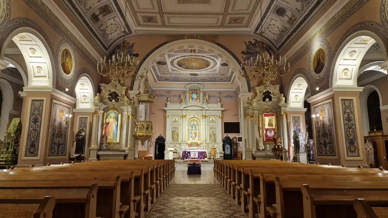 Wnętrze kościoła z rzędami drewnianych ławek. Oświetlenie kościołów podkreśla bogate zdobienia ścian i sklepienia, malowidła oraz ołtarz.