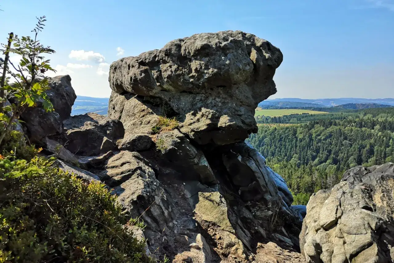 Wielkie, skalne formacje, przypominające białe skały, górują nad zieloną doliną.