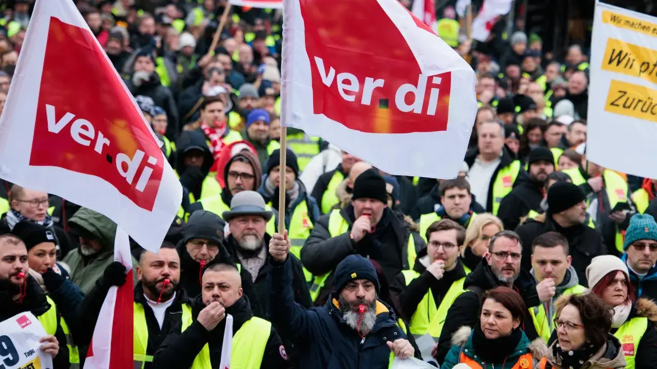 Menschen demonstrieren mit Fahnen, auf denen 