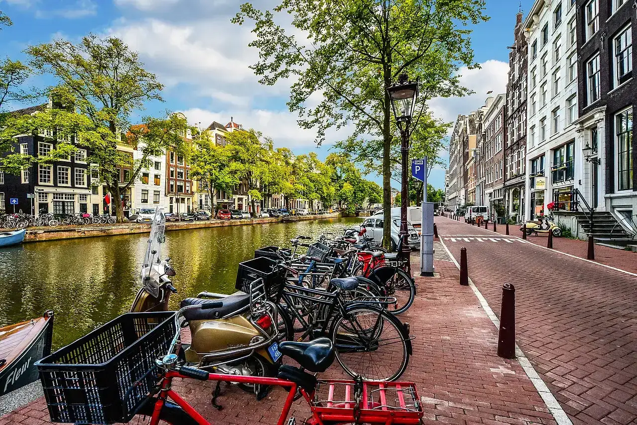 Fahrräder und Roller säumen einen Kanal in Amsterdam, ein Bild des