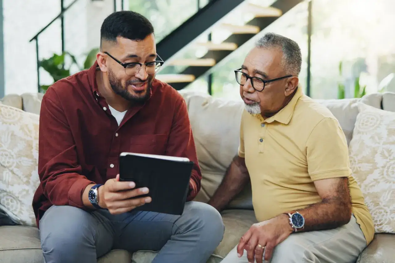 Ein Mann zeigt seinem Vater auf einem Tablet Informationen über Lewy-Body-Demenz. Sie tauschen sich aus, um die Erkrankung besser zu verstehen.