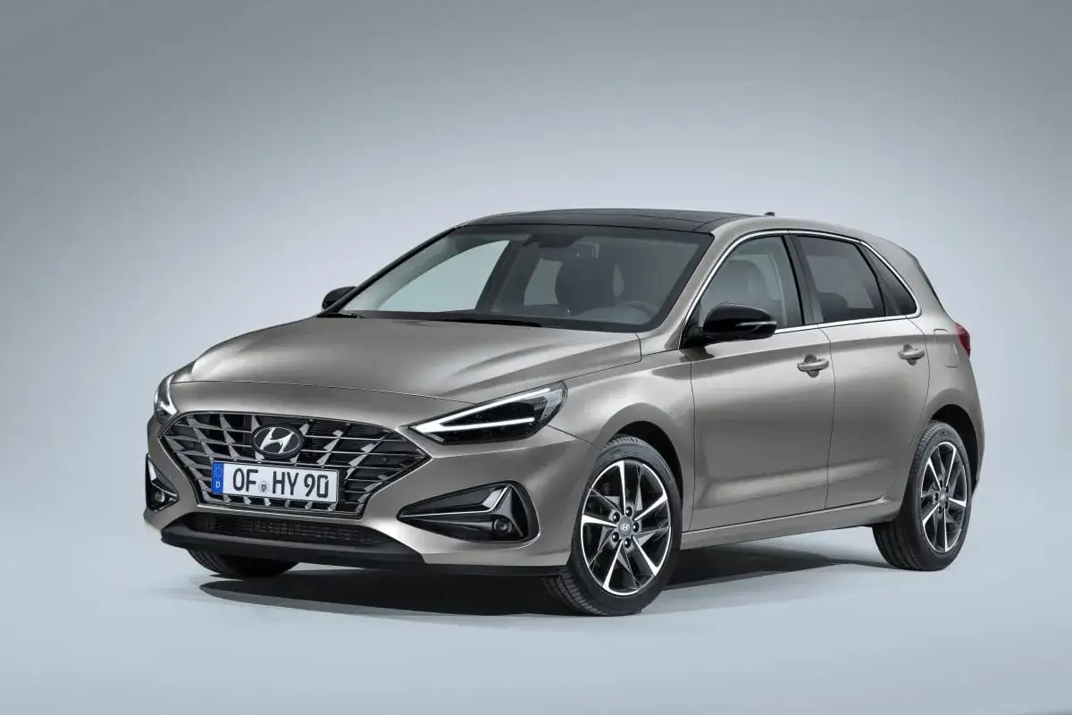 Nowy Hyundai i30 w kolorze szarym, z czarnym dachem i felgami, prezentuje się elegancko na jasnym tle.