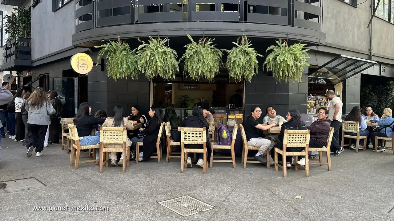 Menschen genie&szlig;en das Leben in einem Caf&eacute; in Mexiko-Stadt. H&auml;ngende Pflanzen schm&uuml;cken die Fassade.