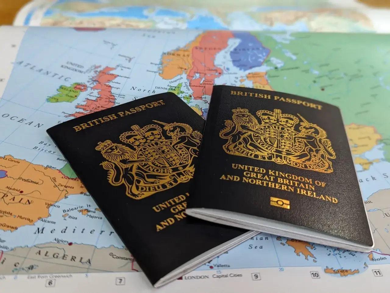Dwa brytyjskie paszporty leżą na mapie Europy. Czy do Wielkiej Brytanii potrzebny jest paszport? Tak, dla podróżujących z zagranicy.