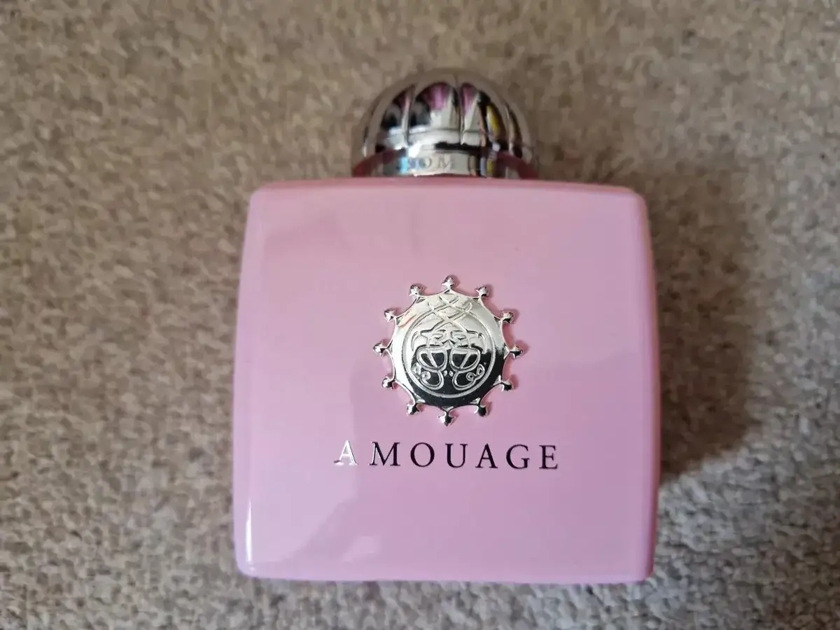 Różowa buteleczka perfum Amouage z metalowym logo. Zapach Blossom Love, jak pierwszy pocałunek.