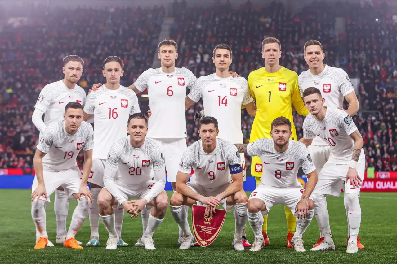Drużyna narodowa Polski w piłce nożnej, gotowa do meczu z Czechami. Piłkarze w białych strojach z orłem na piersi.