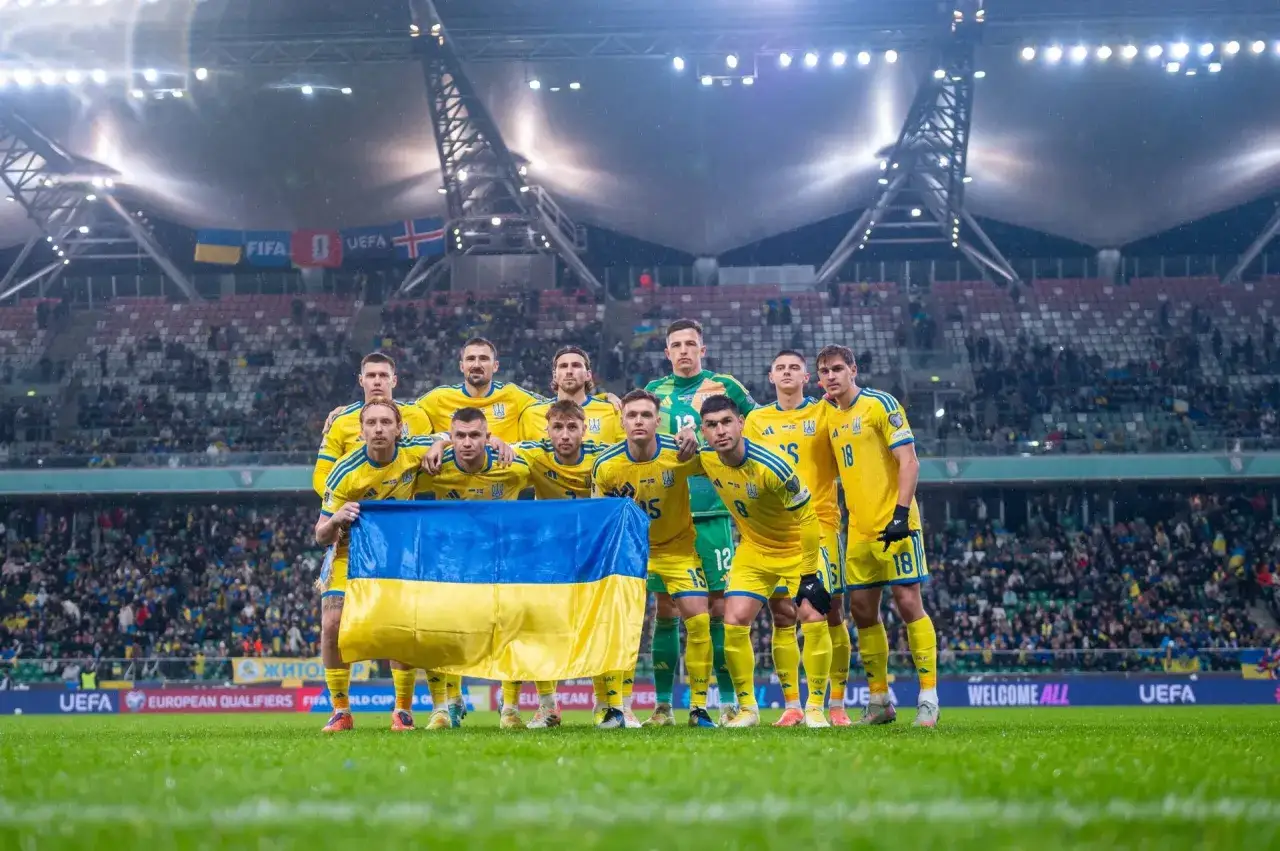 Piłkarze Ukrainy w żółtych strojach, z flagą narodową, gotowi do barażu o awans na mistrzostwa.