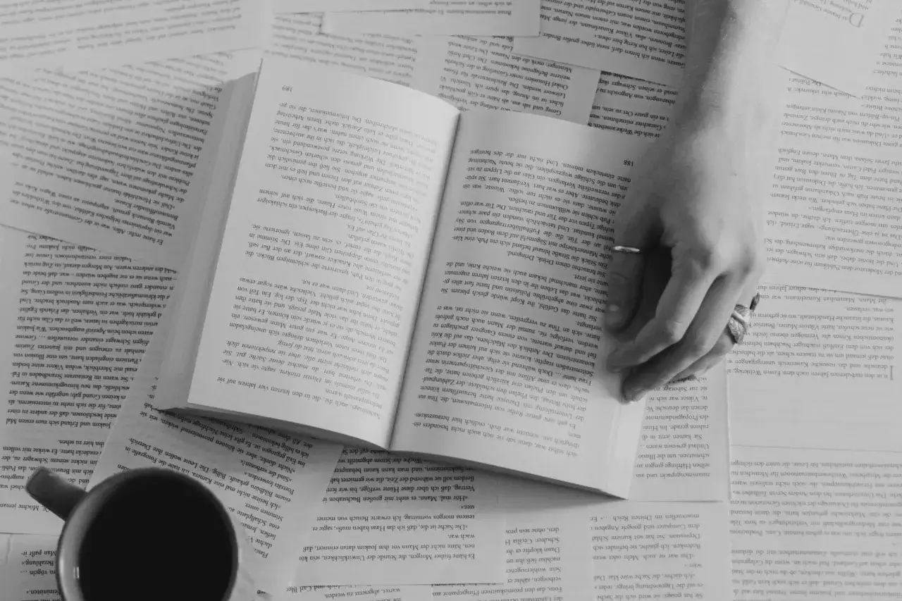 Dłoń na otwartej książce. Złe formatowanie tekstu, małe marginesy i gęsty druk utrudniają czytanie, męcząc wzrok.