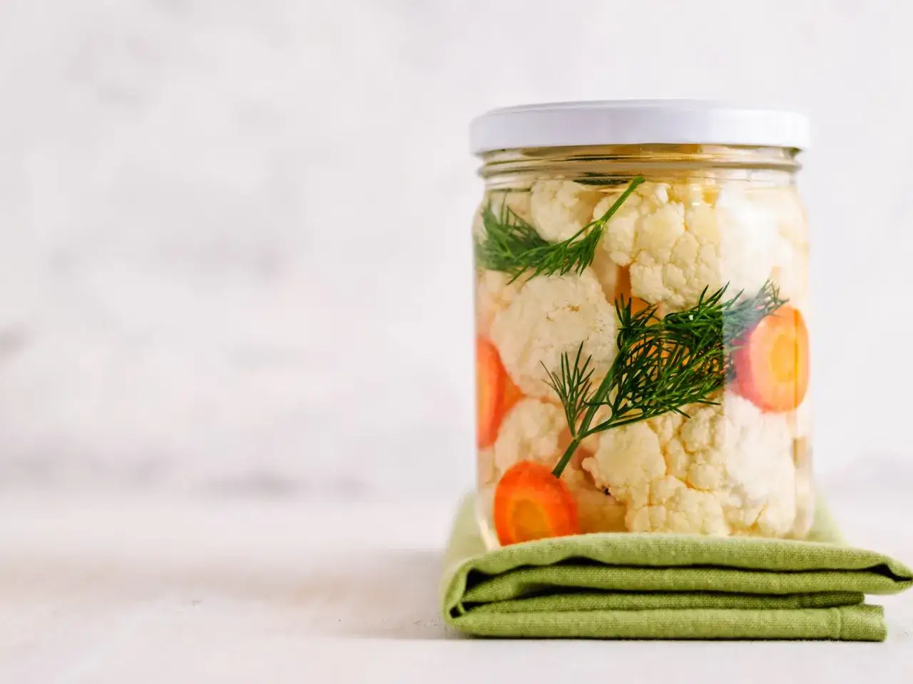 Glas mit Blumenkohl und Karottenstücken, bereit zum Blumenkohl fermentieren. Frischer Dill rundet die Zubereitung ab.