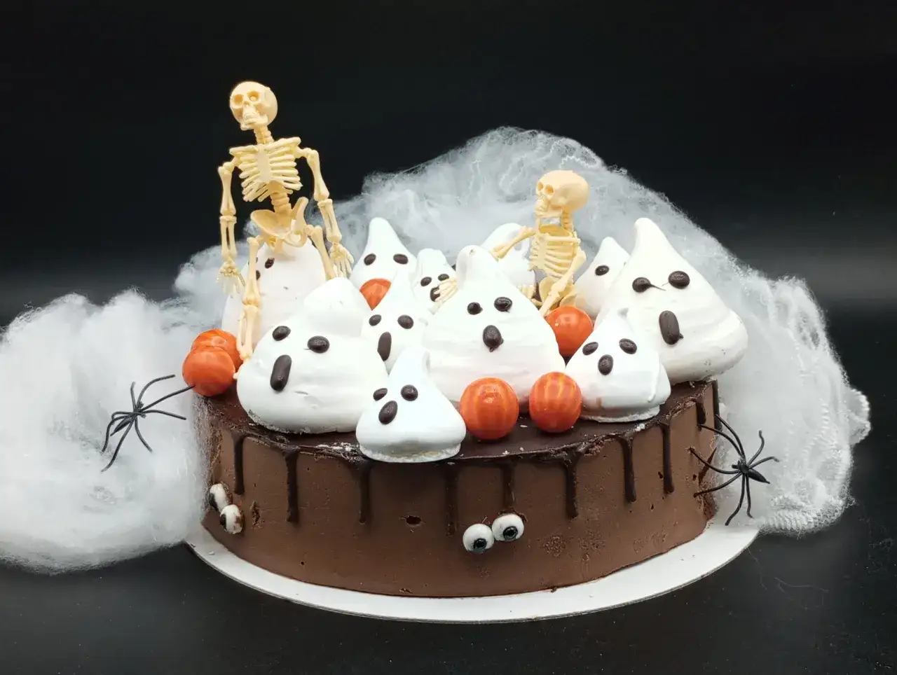 Tartas de Halloween originales: un pastel de chocolate cubierto de fantasmas de merengue, calabazas y esqueletos, rodeado de telara&ntilde;as y ara&ntilde;as.