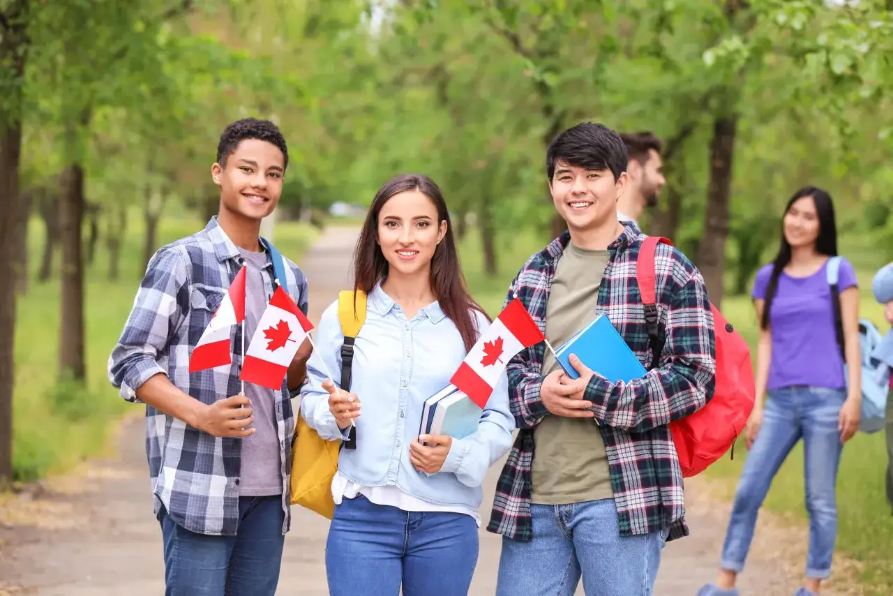 Jóvenes sonrientes con banderas de Canadá, listos para un intercambio estudiantil.