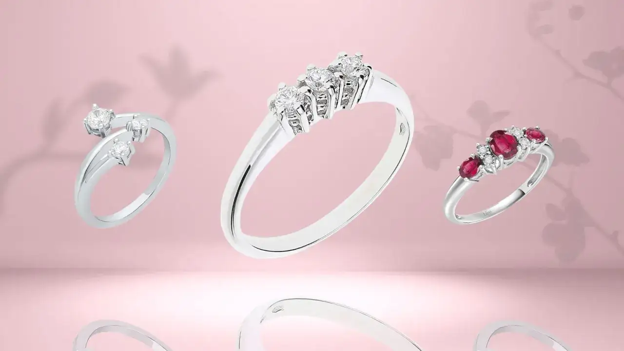 Tre anelli in oro bianco: uno con diamanti disposti a spirale, uno con tre diamanti che simboleggiano il **trilogy significato** (passato, presente, futuro), e uno con rubini e diamanti.