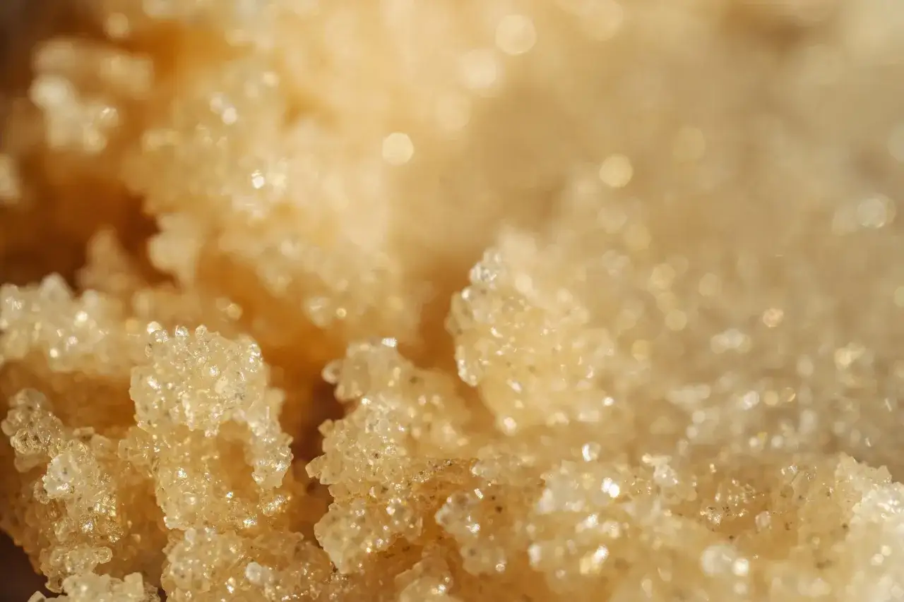 Primo piano di cristalli dorati scintillanti, perfetti per capire quante volte fare lo scrub corpo per una pelle luminosa.