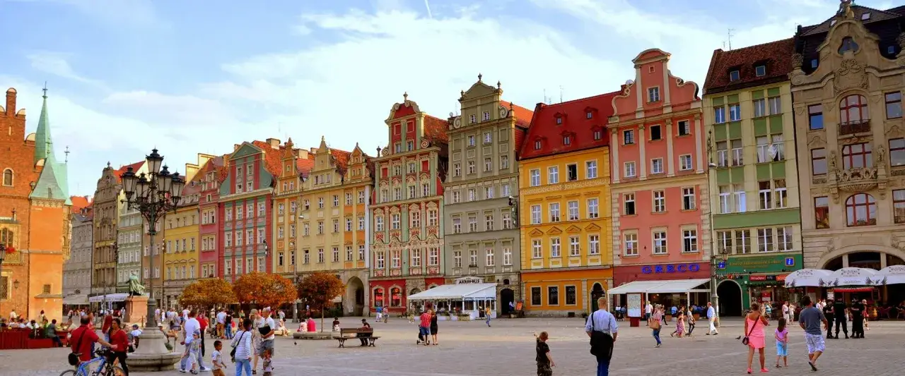 Bunter Marktplatz in Polen. Ein polnischer Bus parkt in der N&auml;he der bunten H&auml;user. Menschen spazieren und genie&szlig;en die Sonne.