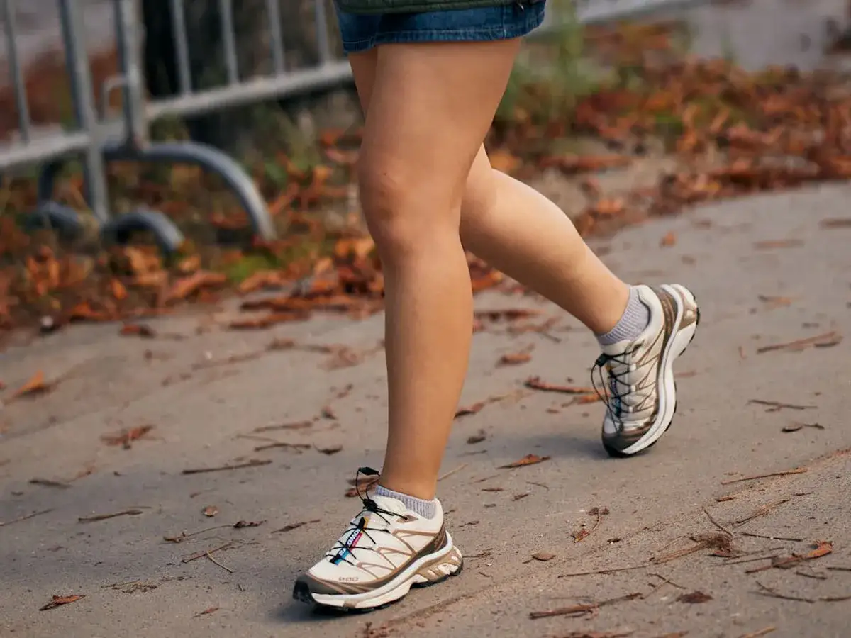 Piernas de mujer caminando con zapatillas deportivas, listas para la aventura.
