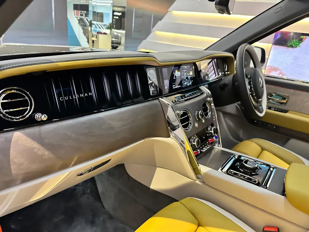 Wnętrze Rolls-Royce Cullinan, z żółtymi skórzanymi siedzeniami i panelem z napisem
