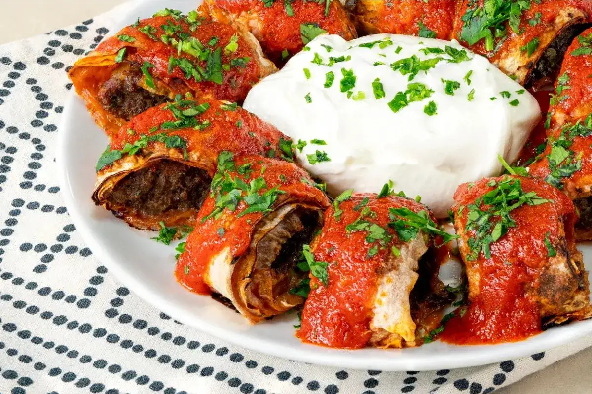 En tallrik med beyti kebab, t&auml;ckt med tomats&aring;s och persilja, serveras med en klick yoghurt.