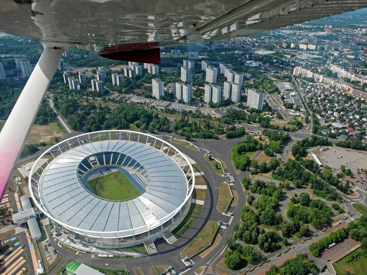 Widok z lotu ptaka na jeden z największych stadionów w Polsce, otoczony zielenią i miejską zabudową.