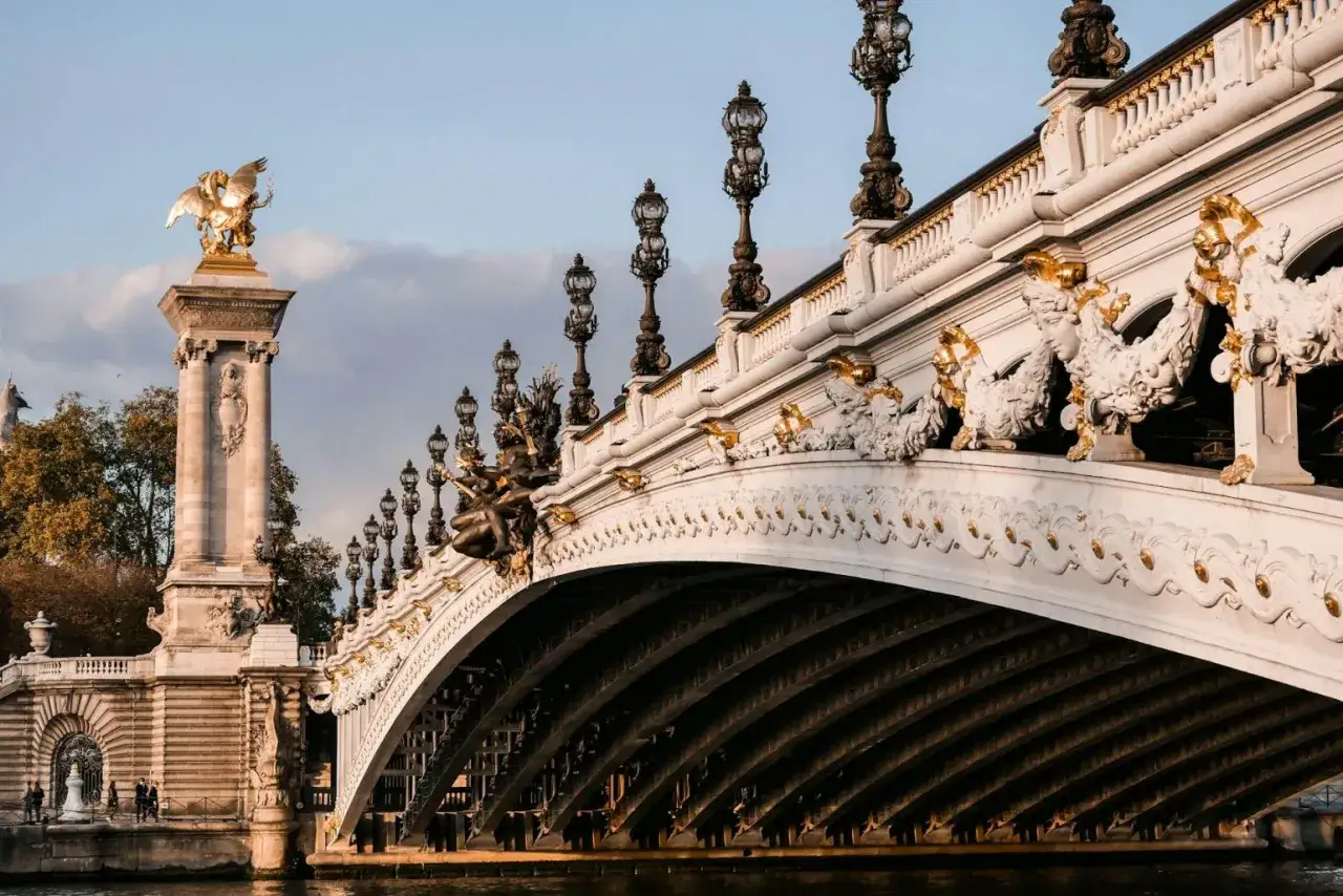 Magnifique balade sur Seine à Paris, le Pont Alexandre III orné de ses lampadaires et sculptures dorées, sous un ciel bleu et nuageux.
