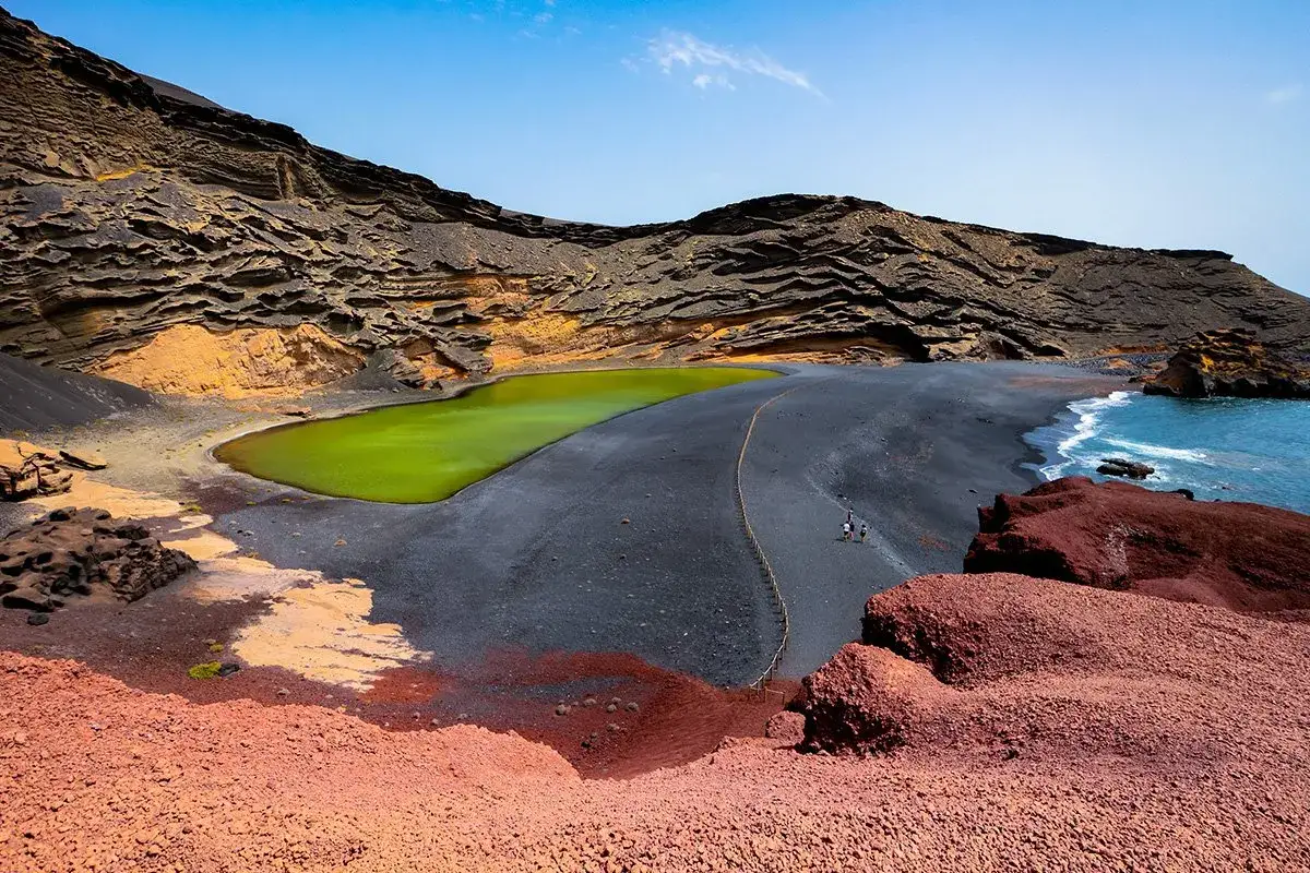 Wulkaniczne krajobrazy na Lanzarote, kt&oacute;re warto zwiedzać: czarna plaża, zielona laguna i klify.