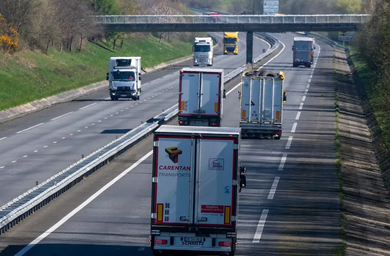 Plusieurs camions circulent sur l'autoroute, certains transportent des marchandises. C'est une journée typique pour travailler sur la route.