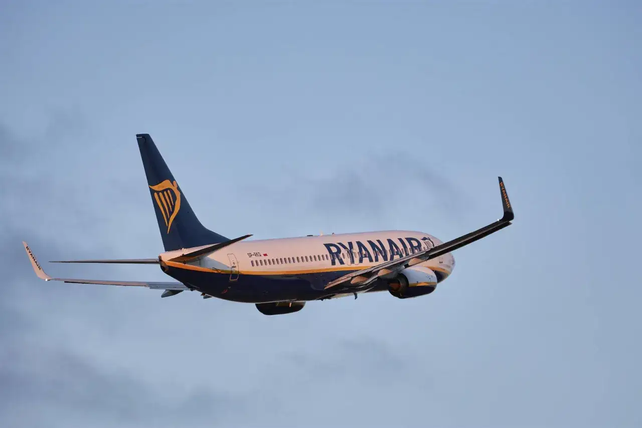 Samolot Ryanair wznosi się na tle błękitnego nieba. Czas sprawdzić, ile się leci na Maltę!
