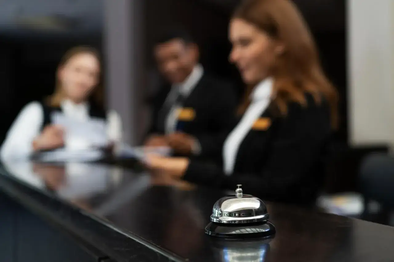 Dzwonek przy recepcji hotelowej, gdzie hotelarz zaw&oacute;d to codzienna praca z gośćmi.