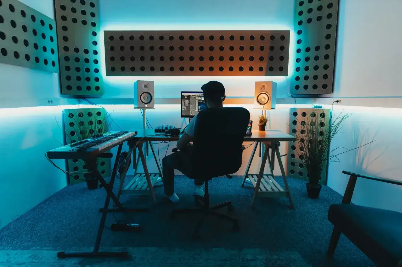 Un beatmaker fran&ccedil;ais cr&eacute;e sa musique dans son studio, entour&eacute; de panneaux acoustiques et d'un &eacute;clairage bleu n&eacute;on.