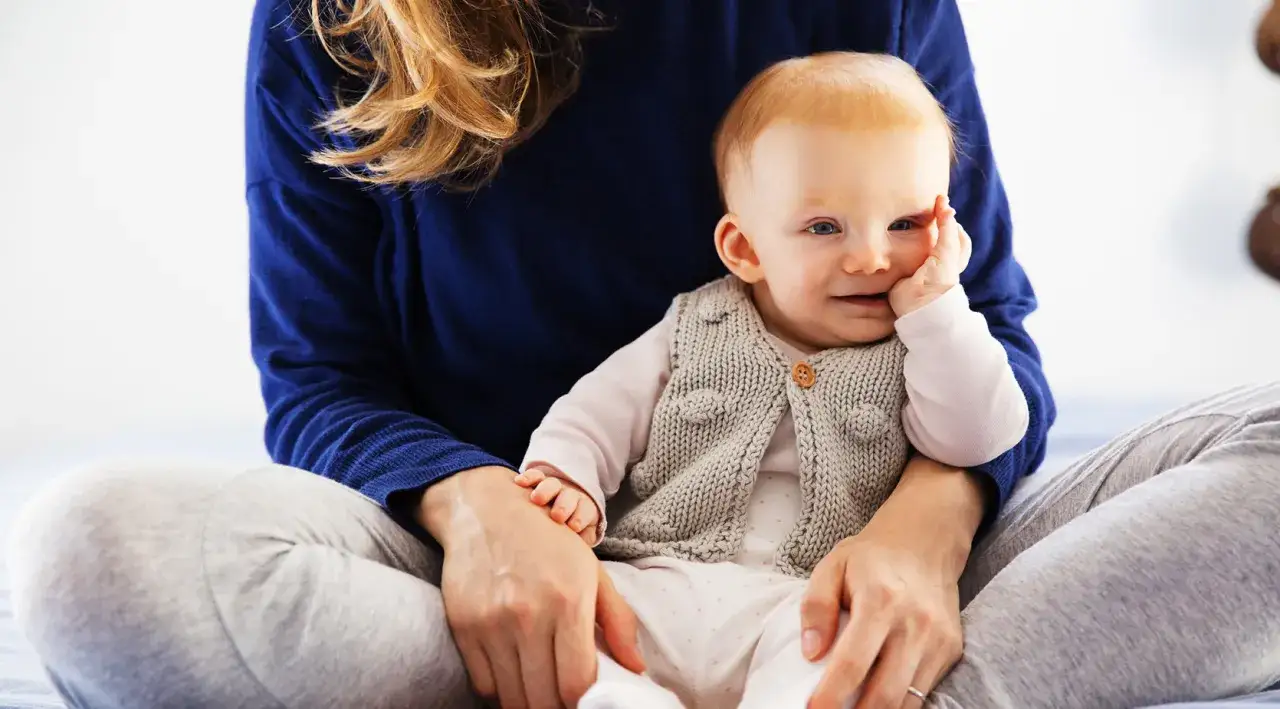 Mama wspiera dziecko, które jeszcze nie siedzi. Troskliwa rehabilitacja i bliskość.