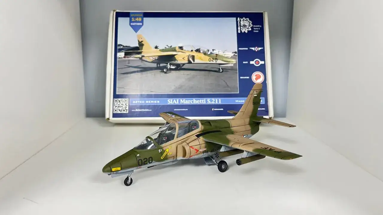 Ein detailliertes Modell eines SIAI Marchetti S.211 Flugzeugs, nummeriert 020, steht vor seiner Verpackung.