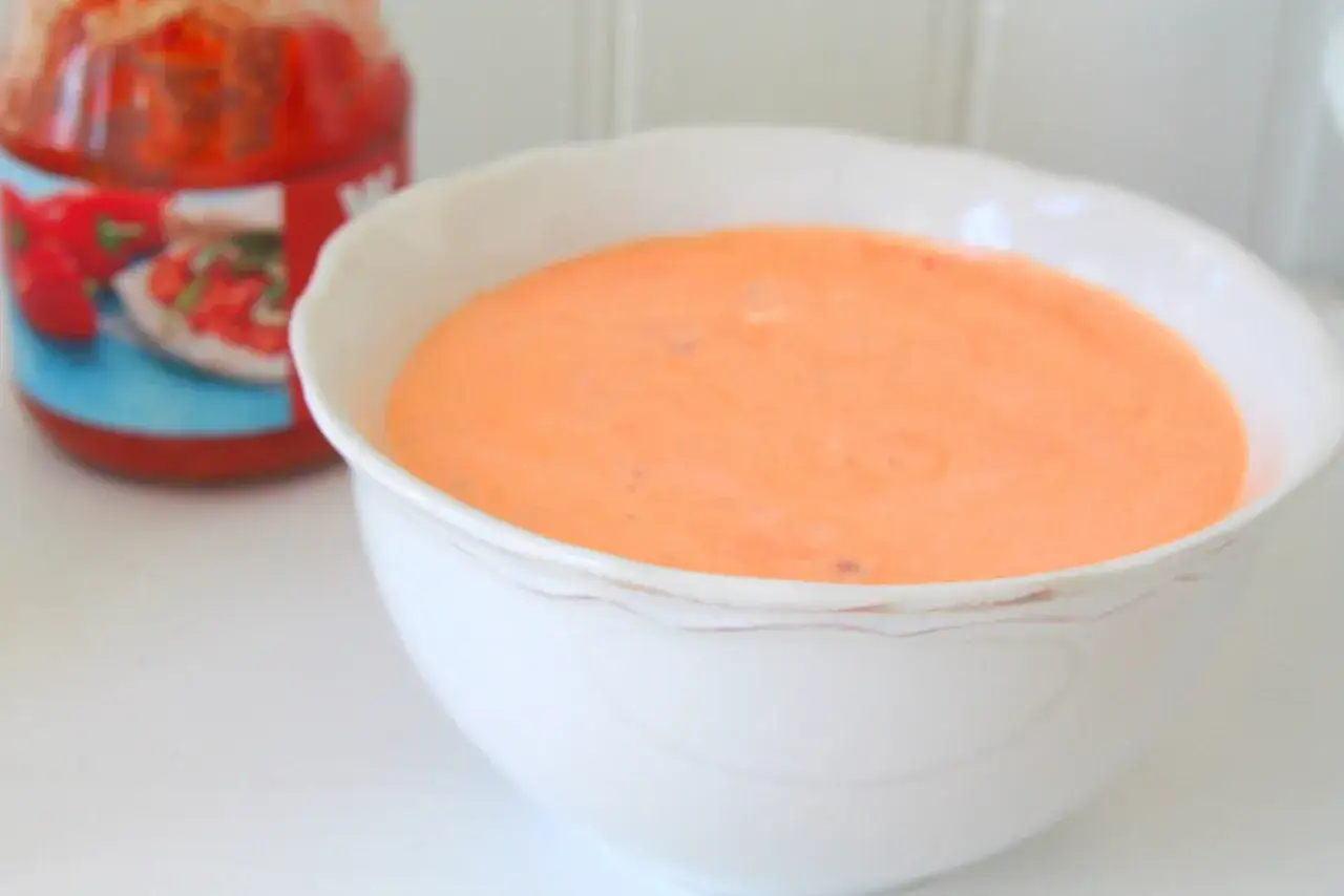 En skål med krämig kall sås, perfekt som tillbehör till grillad kyckling. Denna sås, baserad på crème fraiche, har en härlig orange färg.