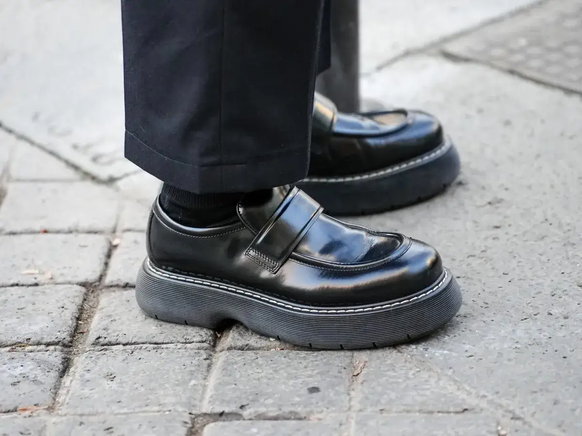 Un par de mocasines negros con suela gruesa y costuras blancas, un ejemplo de los modernos tipos de mocasines.
