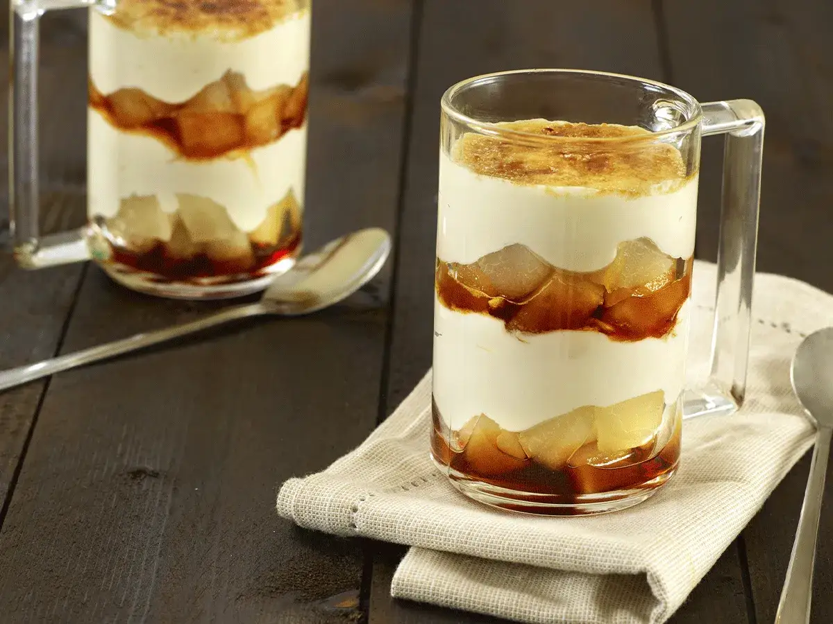 Un délicieux tiramisu poire, superposé en couches crémeuses et morceaux de poire caramélisée, servi dans un verre.