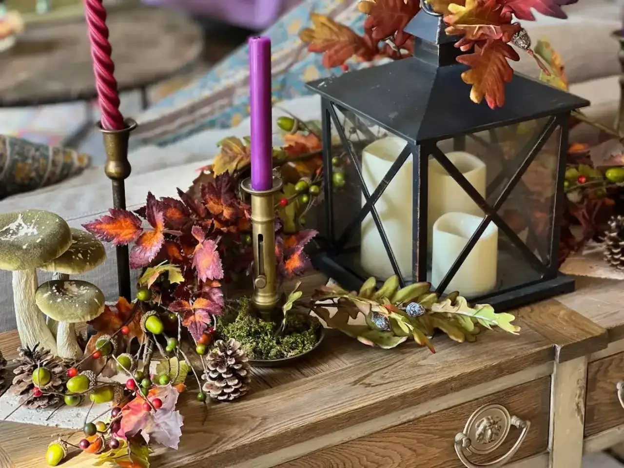 D&eacute;coration d'automne avec des feuilles d'arbre, des champignons, des pommes de pin et des bougies dans une lanterne.