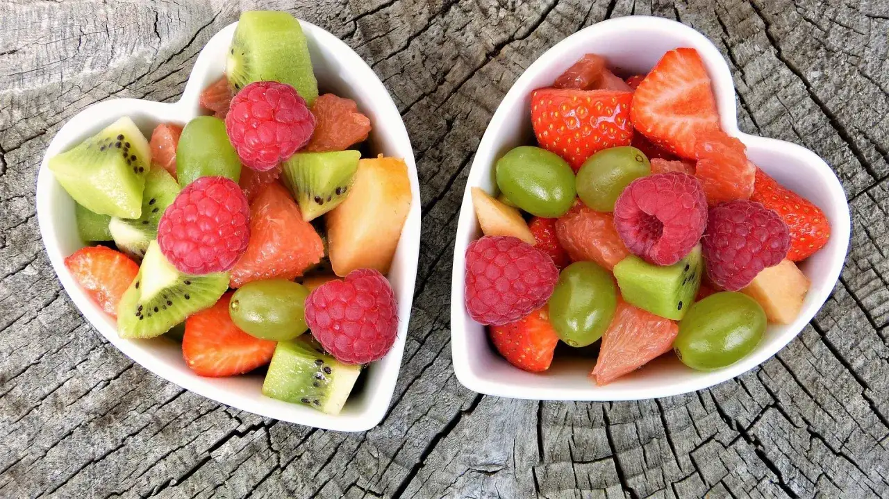 Dwa sercowate talerzyki pełne kolorowych, niskokalorycznych przekąsek: malin, kiwi, winogron, truskawek i grejpfruta.
