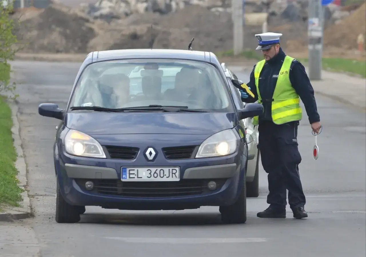 Policjant zatrzymuje niebieskiego Renault Scenic. Kierowca próbuje uniknąć kontroli, ale funkcjonariusz jest czujny.