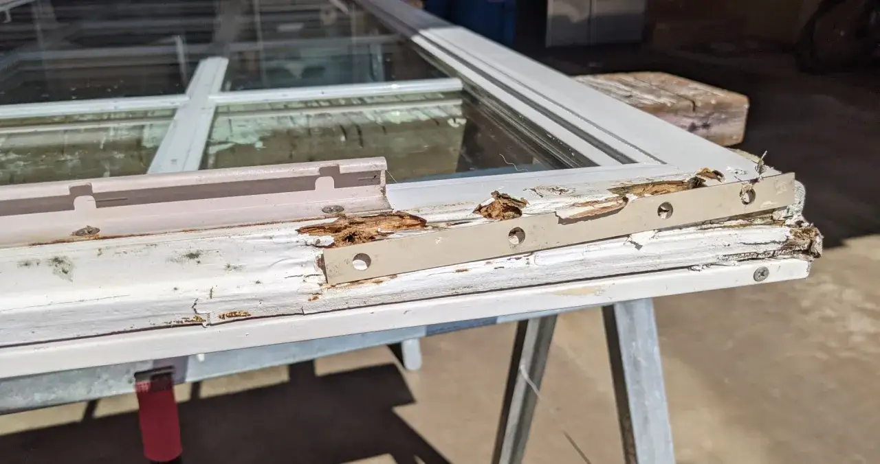 Damaged wood window frame, showing rot and peeling paint, indicating a need for wood window repair.