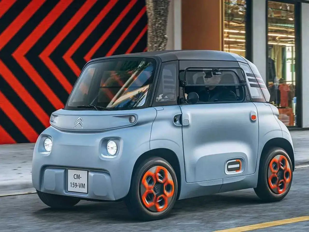 Citroën Ami, un quadriciclo elettrico compatto, sfreccia con stile. Le sue ruote arancioni catturano l'attenzione.