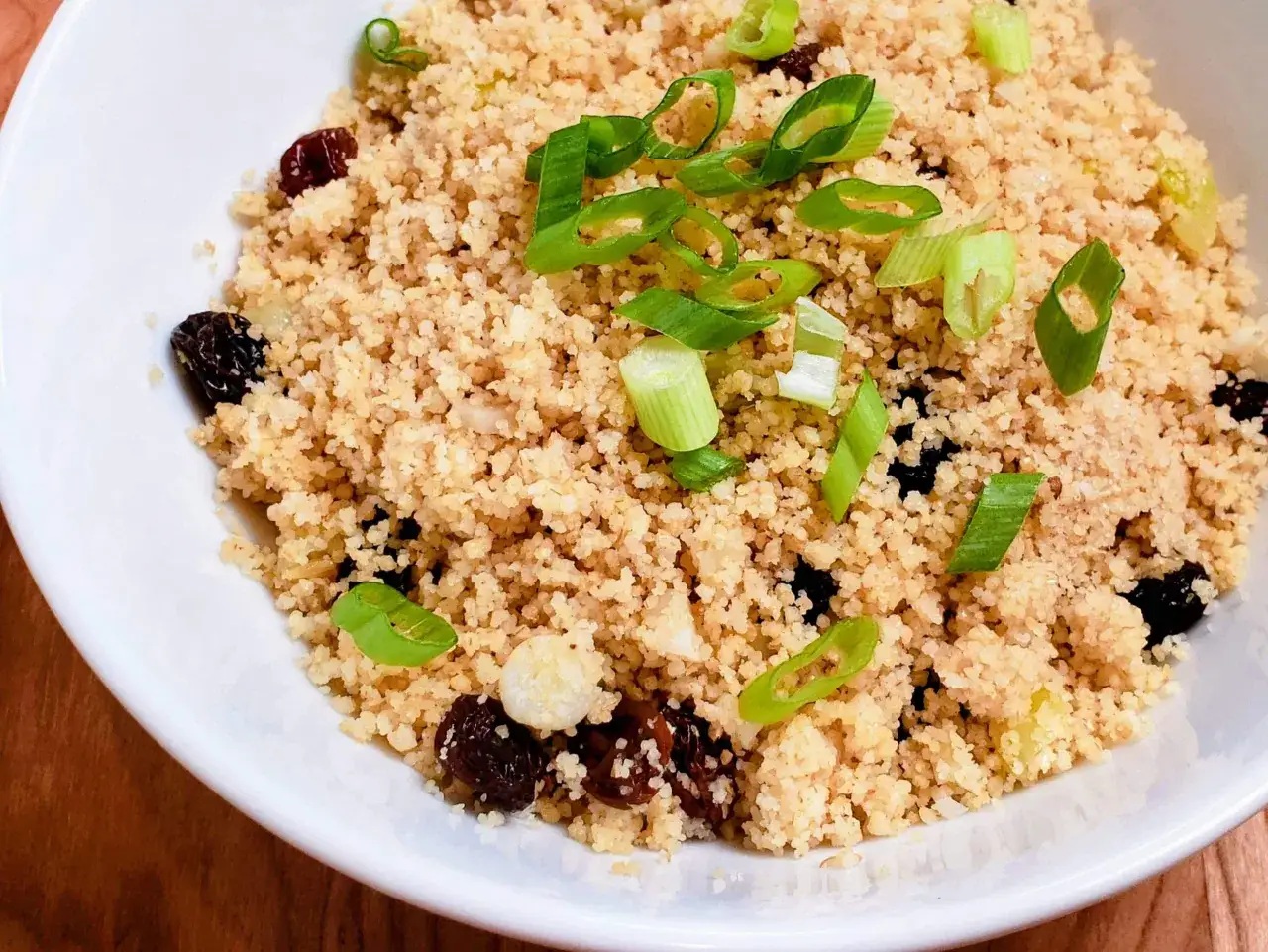 Ein Teller mit köstlichem Couscous mit Rosinen und Frühlingszwiebeln, bereit zum Genießen.