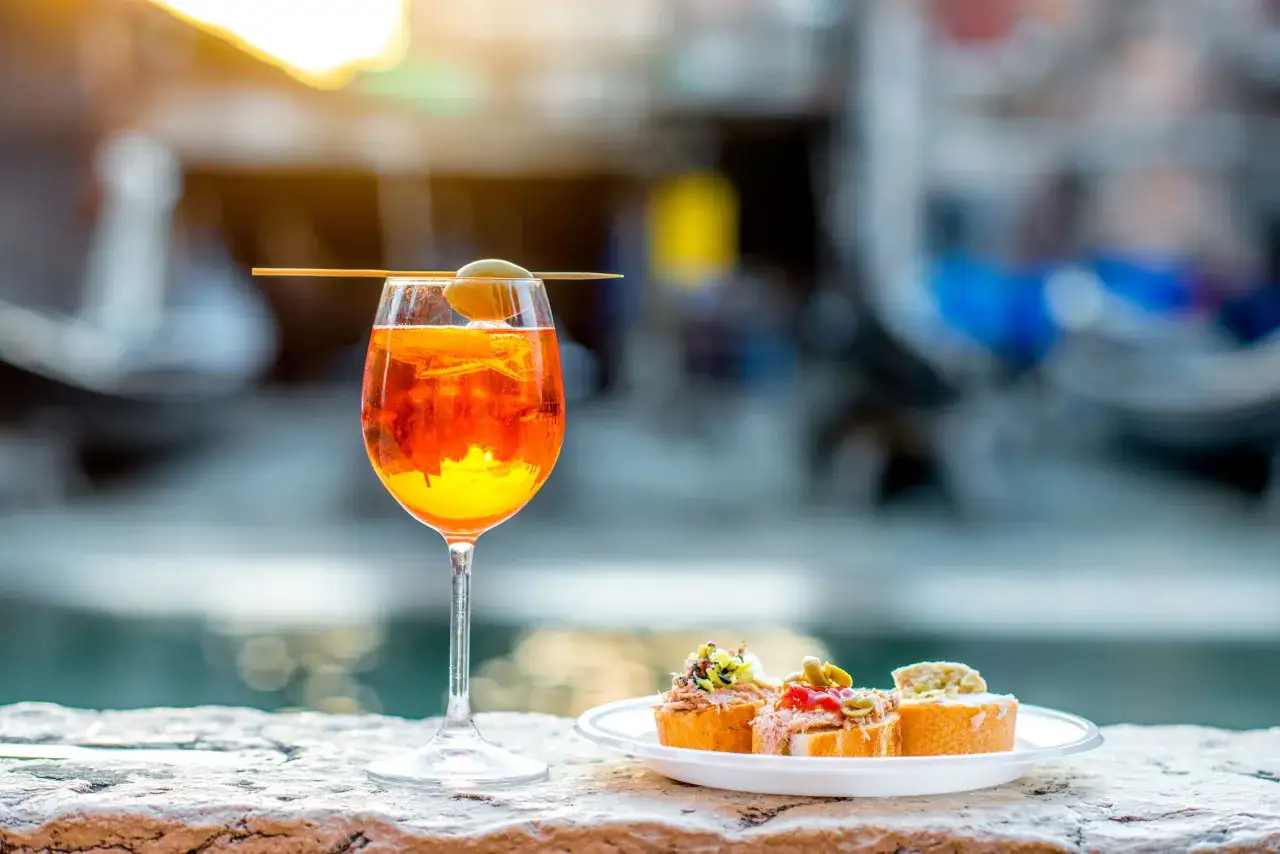 Erfrischender Aperitif mit Oliven und kleinen Snacks, inspiriert von Crodino Rezepten, am Wasser.
