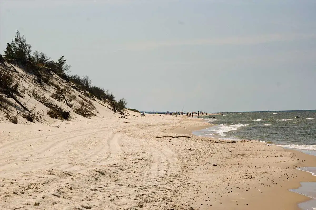 Plaża w Ustce i okolice: piaszczyste wydmy, morze i wypoczywający ludzie. Idealne miejsce na wakacje.