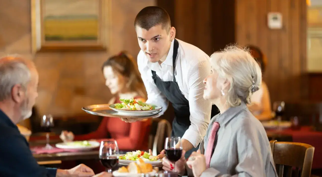 Kelner podaje sałatkę parze przy stoliku. Zastanawiasz się, jaki napiwek w restauracji będzie odpowiedni?