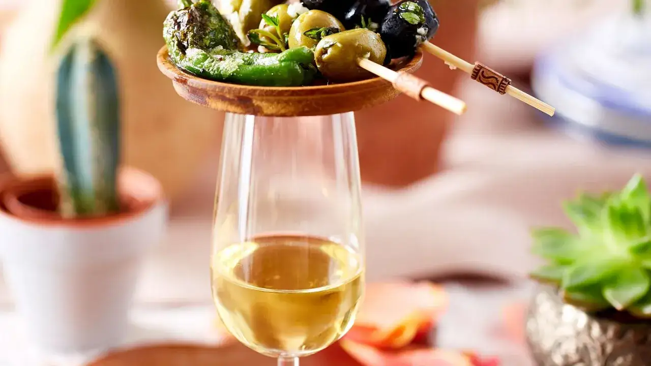 Ein Glas Sherry mit Oliven und Paprika. So trinkt man Sherry: als Aperitif mit Tapas.