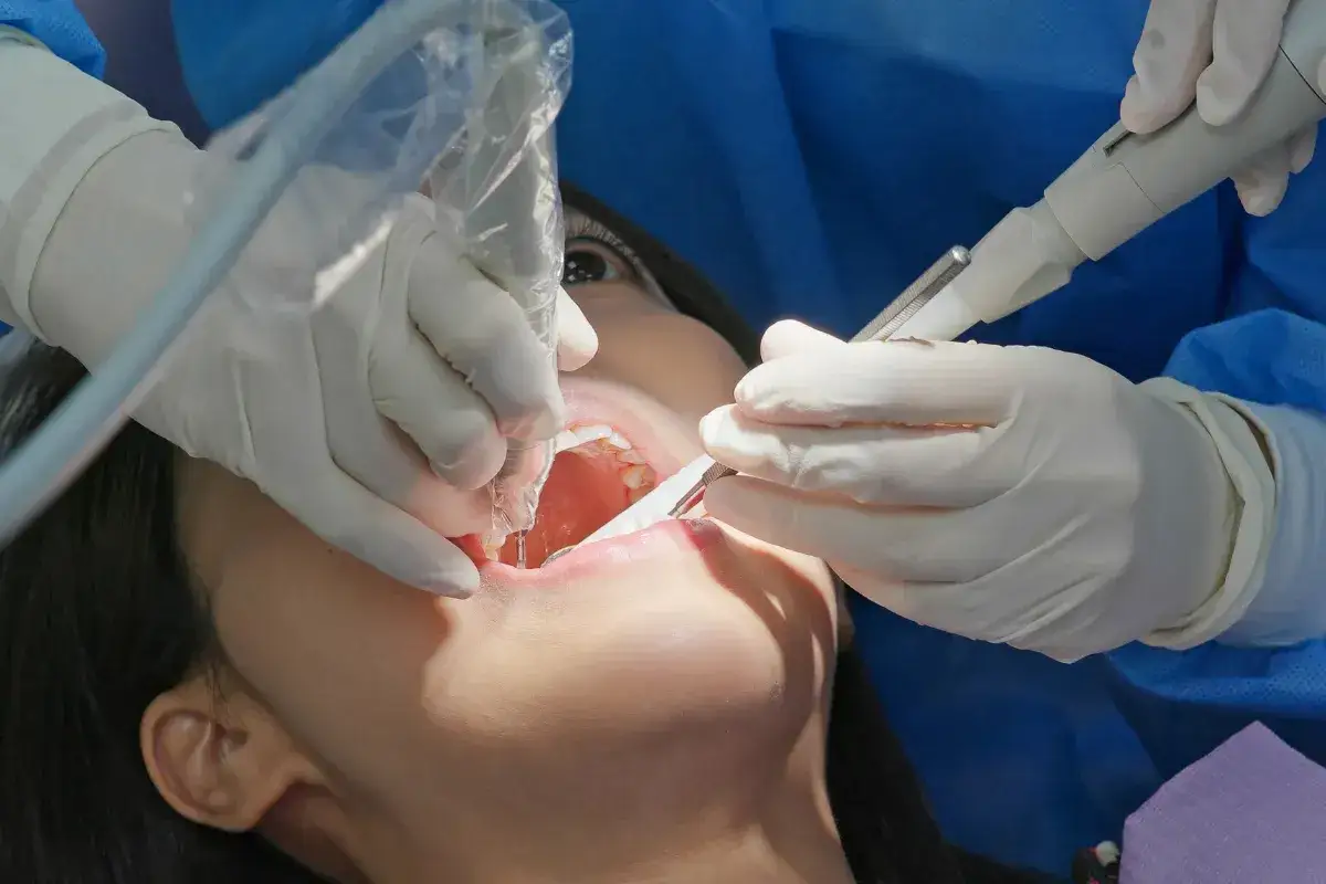 Pacjentka odczuwa ból zęba po plombowaniu przy nagryzaniu. Dentysta pracuje nad jej uzębieniem.