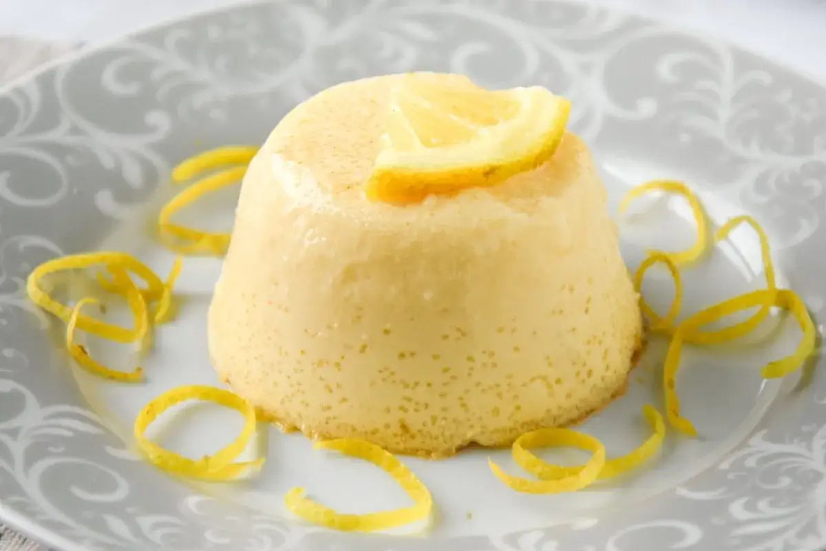 Delicioso flan de limón, coronado con una rodaja de limón y decorado con cáscara de limón en espiral.