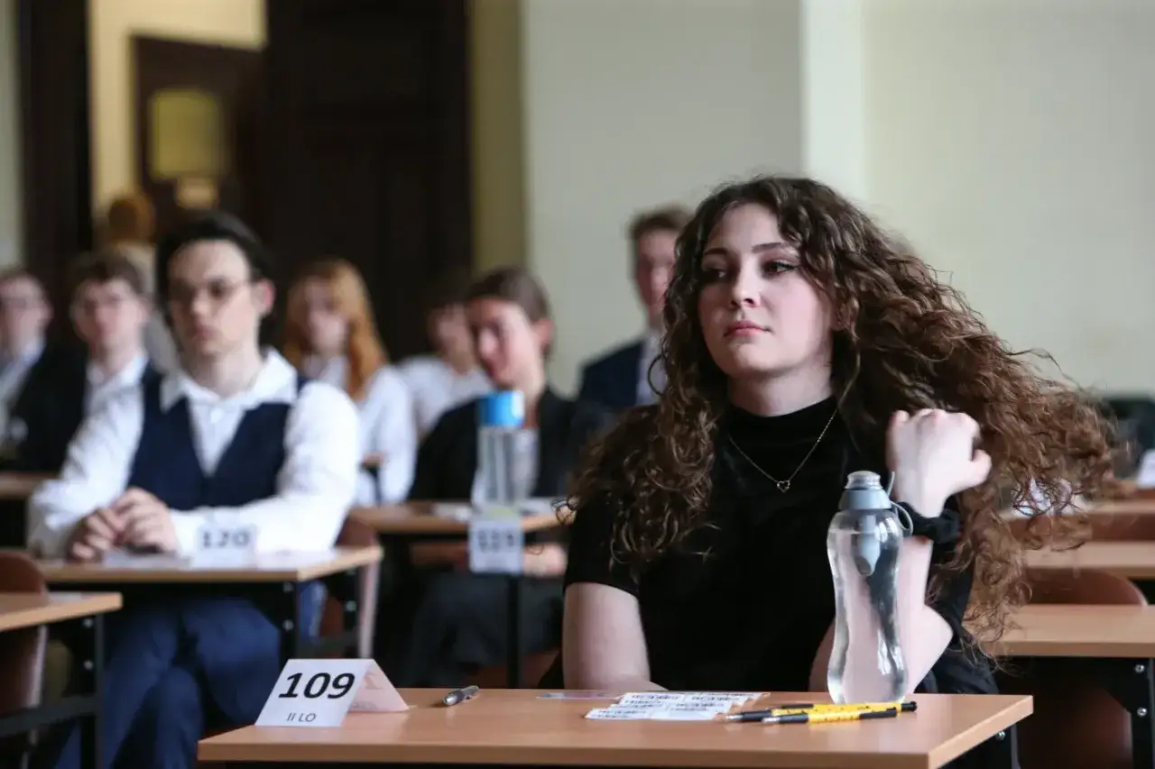 Uczniowie siedzą w sali egzaminacyjnej, zastanawiając się, ile trwa matura z polskiego.