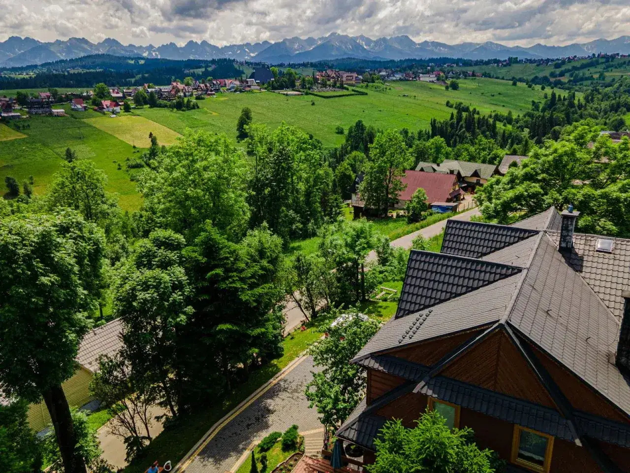 Pokoje gościnne Zosia w Bukowinie Tatrzańskiej. Malowniczy widok na Tatry z zielonych wzg&oacute;rz i tradycyjnych dom&oacute;w.