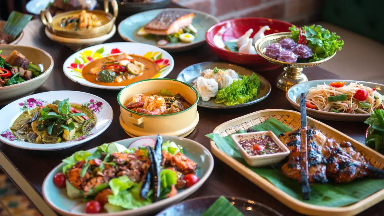 Bogactwo smaków! Na stole królują najpopularniejsze dania kuchni tajskiej: zielone curry, sałatka z papai, grillowany kurczak i krewetki w aromatycznym sosie.