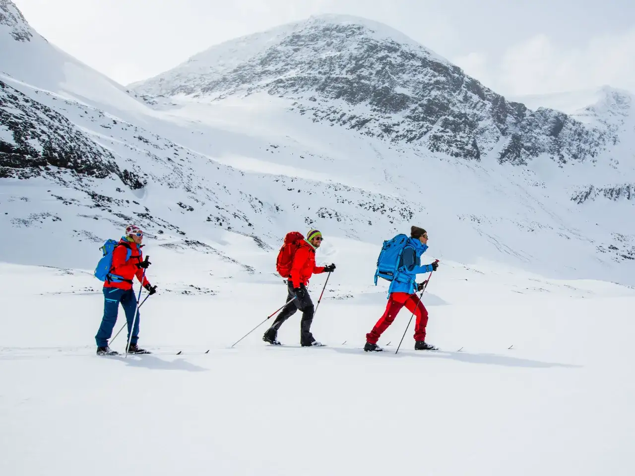 Tre personer &aring;ker skidor i ett sn&ouml;igt landskap n&auml;ra Abisko. De b&auml;r ryggs&auml;ckar och anv&auml;nder skidstavar.